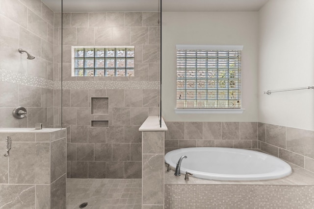 bathroom featuring a wealth of natural light, a bath, and a walk in shower