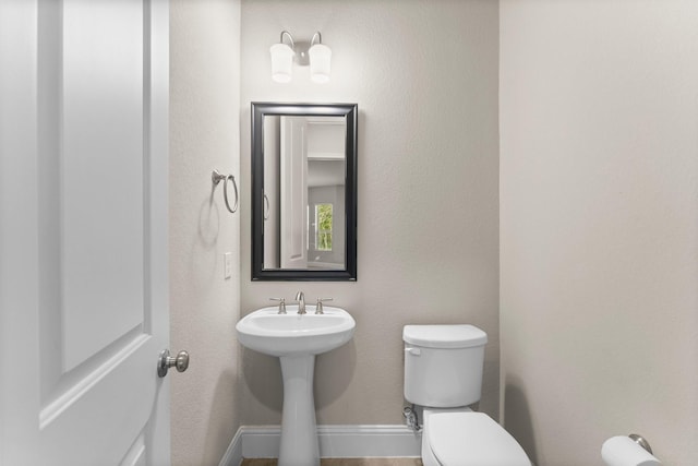 bathroom with toilet, a sink, and baseboards