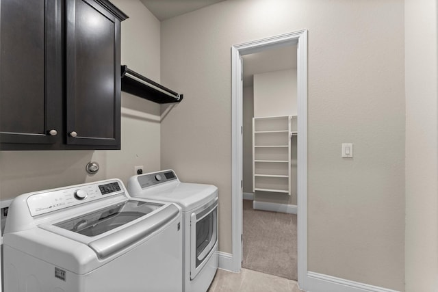 washroom with light carpet, washing machine and clothes dryer, baseboards, and cabinet space