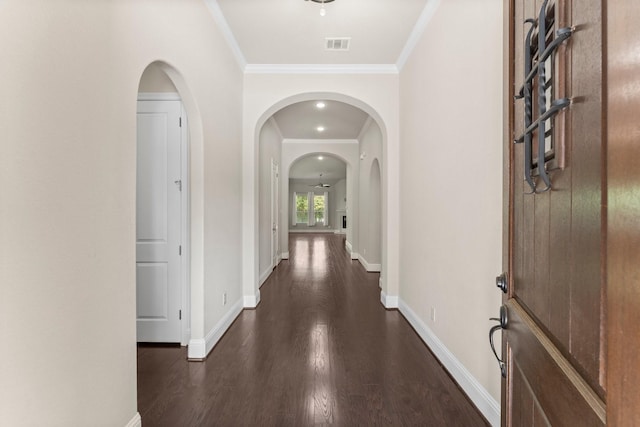 corridor featuring dark wood-type flooring, visible vents, baseboards, and arched walkways