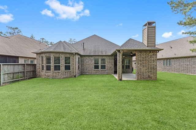 back of property featuring a patio, a chimney, brick siding, fence, and a lawn