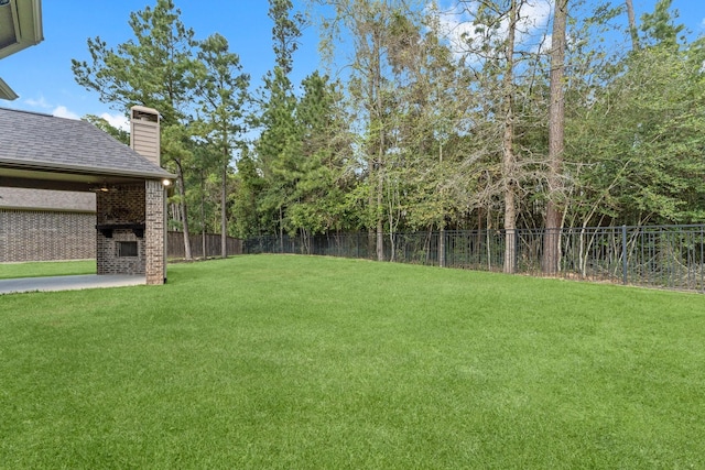 view of yard with a fenced backyard and a fireplace