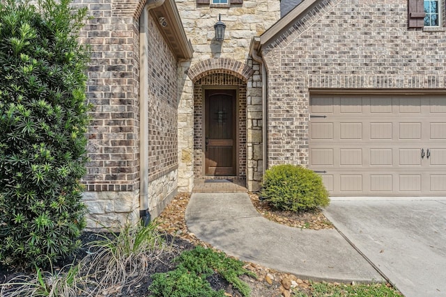 entrance to property with driveway, stone siding, and a garage