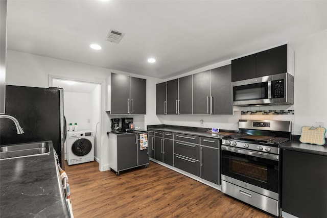 5808 Community Dr, Houston, TX 77005 - kitchen featuring a sink, dark countertops, washer / dryer, visible vents, and appliances with stainless steel finishes