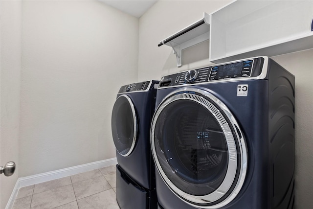 laundry area featuring baseboards, light tile patterned floors, laundry area, and washing machine and clothes dryer
