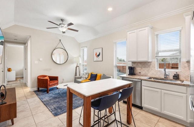 kitchen with light tile patterned floors, dishwasher, a sink, ceiling fan, and backsplash