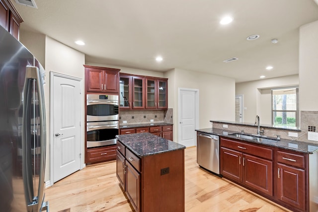 155 Pronghorn Pl, Montgomery, TX 77316 - kitchen with visible vents, light wood finished floors, a kitchen island, appliances with stainless steel finishes, and a sink