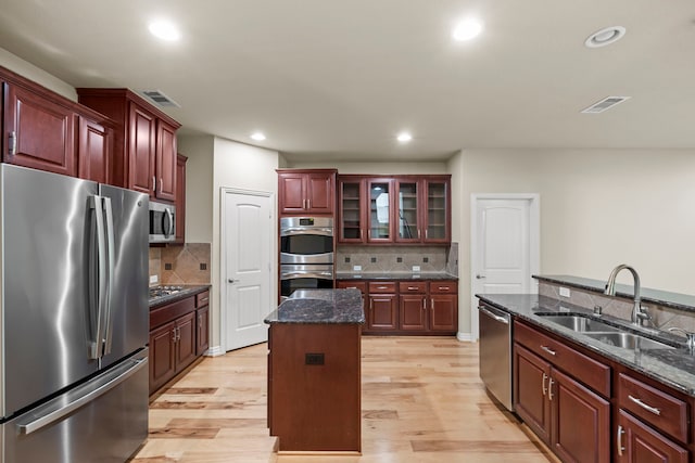 155 Pronghorn Pl, Montgomery, TX 77316 - kitchen featuring a center island, a sink, reddish brown cabinets, light wood finished floors, and appliances with stainless steel finishes
