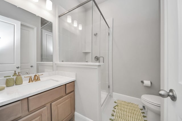 full bath featuring a shower stall, baseboards, toilet, and vanity