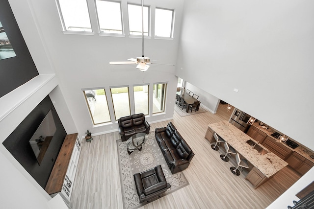 10015 Crescent Wood Dr, Missouri City, TX 77459 - living room featuring a high ceiling, a ceiling fan, baseboards, and wood finished floors