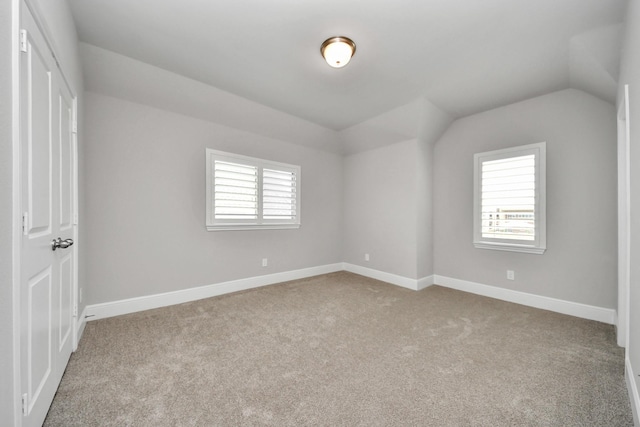 unfurnished bedroom featuring baseboards, lofted ceiling, carpet flooring, and multiple windows