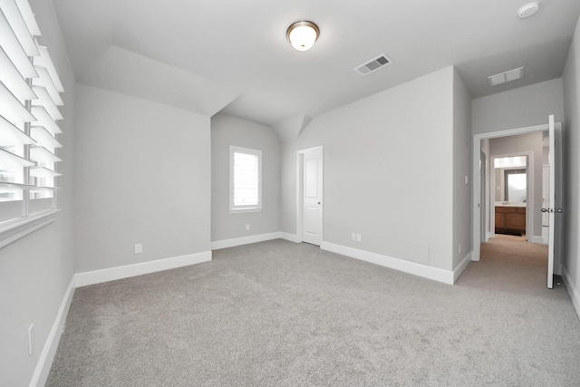 unfurnished bedroom with carpet, baseboards, vaulted ceiling, and visible vents