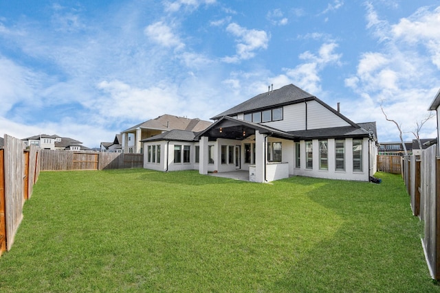 rear view of house with a fenced backyard, a patio, a shingled roof, and a lawn