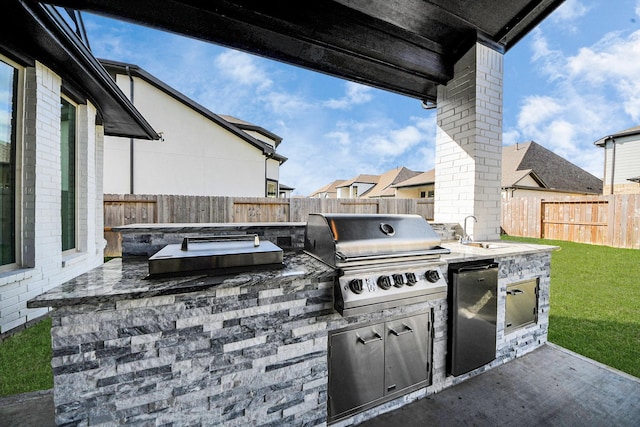 view of patio featuring a grill, a fenced backyard, exterior kitchen, and a sink