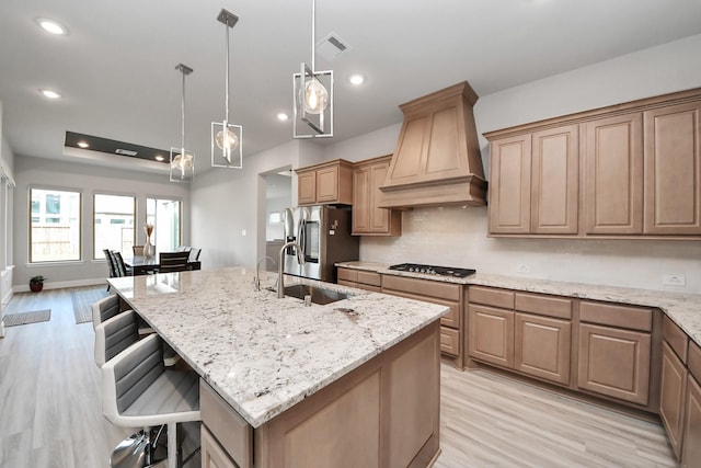10015 Crescent Wood Dr, Missouri City, TX 77459 - kitchen with stainless steel appliances, custom range hood, light wood-style floors, light stone countertops, and a kitchen bar