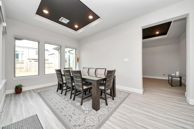 dining area with a raised ceiling, baseboards, and visible vents