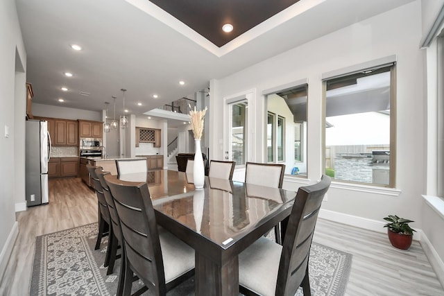 dining area featuring baseboards, light wood-style floors, and recessed lighting