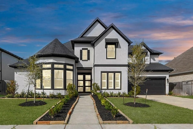 view of front of house with concrete driveway, fence, stucco siding, and a yard