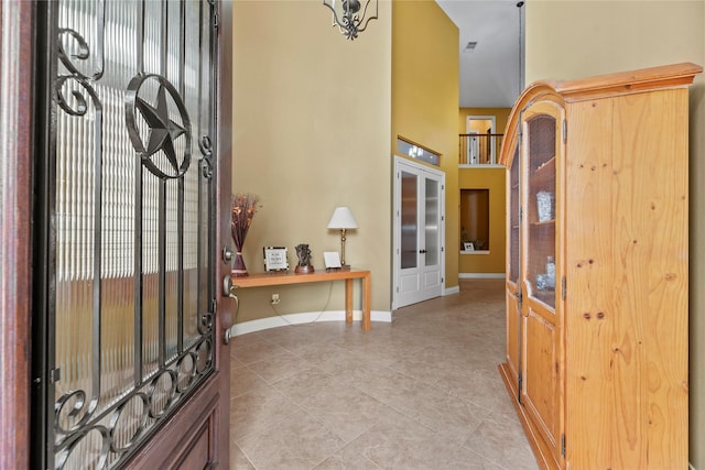 entrance foyer with a high ceiling, light tile patterned floors, and baseboards