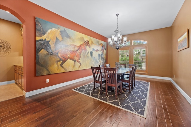 dining room featuring baseboards, arched walkways, wood finished floors, and an inviting chandelier