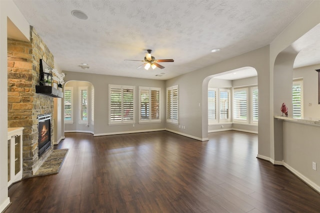 17310 Calico Peak Way, Cypress, TX 77433 - unfurnished living room featuring a ceiling fan, a fireplace, dark wood-style flooring, baseboards, and a textured ceiling
