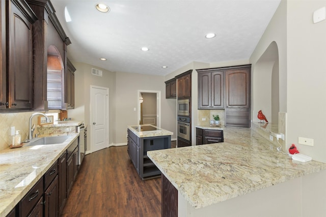 17310 Calico Peak Way, Cypress, TX 77433 - kitchen featuring stainless steel appliances, a sink, arched walkways, dark wood finished floors, and backsplash
