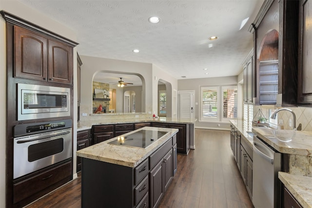 17310 Calico Peak Way, Cypress, TX 77433 - kitchen with stainless steel appliances, arched walkways, backsplash, a peninsula, and dark wood finished floors
