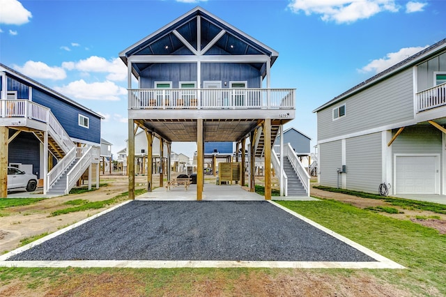 1079 Johnson Rd, Gilchrist, TX 77617 - view of front of house featuring stairs, a carport, board and batten siding, and gravel driveway