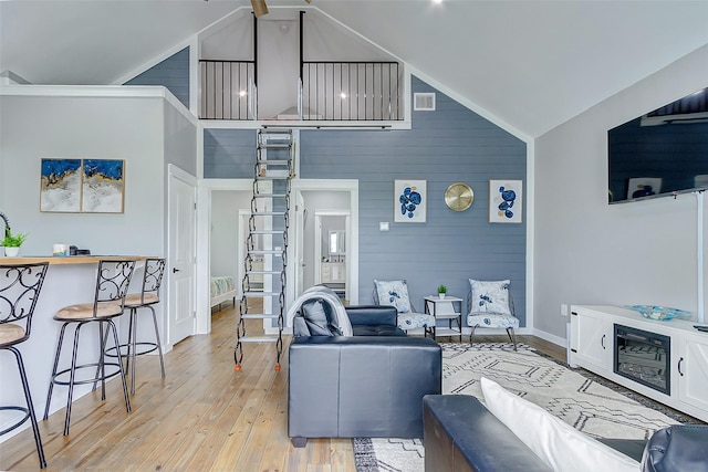 1079 Johnson Rd, Gilchrist, TX 77617 - living room featuring light wood-style floors, baseboards, wood walls, and high vaulted ceiling