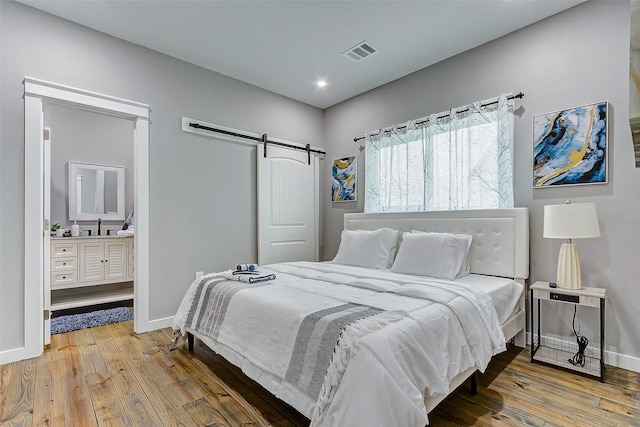 1079 Johnson Rd, Gilchrist, TX 77617 - bedroom featuring a barn door, wood-type flooring, baseboards, recessed lighting, and a sink