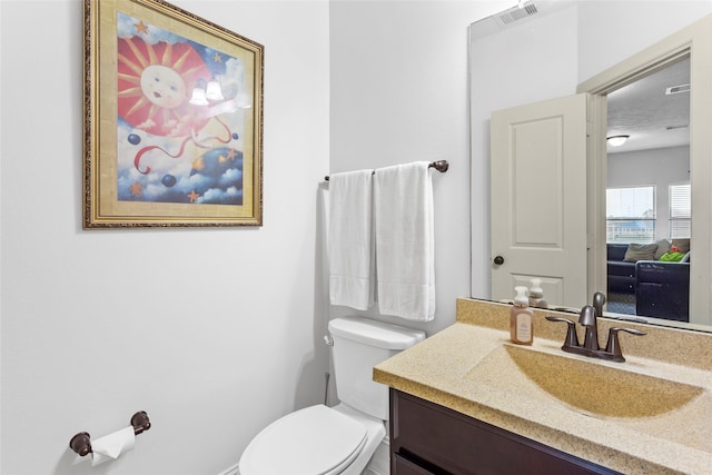 half bath featuring visible vents, toilet, and vanity
