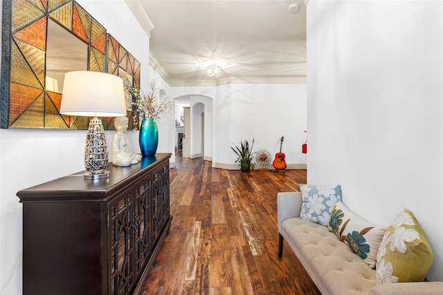 hallway featuring arched walkways, crown molding, baseboards, and wood finished floors