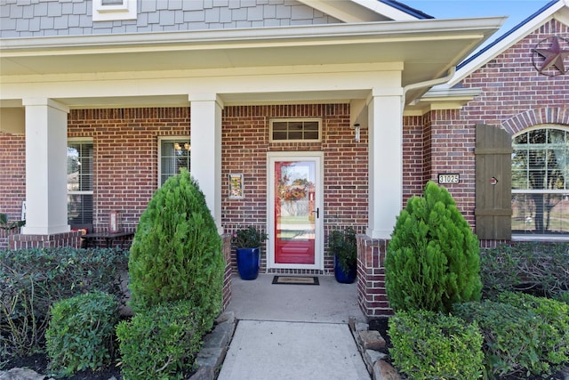 property entrance featuring covered porch and brick siding