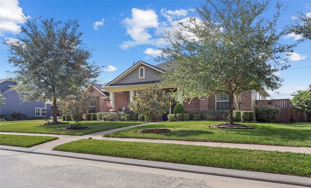 obstructed view of property with a front lawn, fence, and brick siding