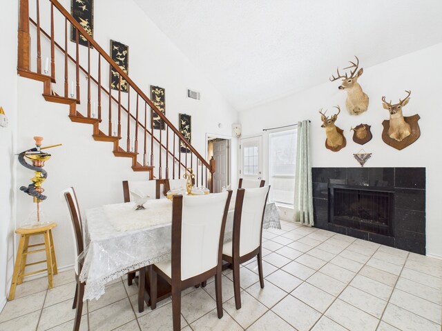 13523 Pasa Robles Ln, Houston, TX 77083 - unfurnished dining area with visible vents, stairs, tile patterned floors, a tiled fireplace, and lofted ceiling