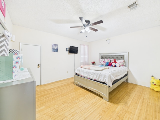 13523 Pasa Robles Ln, Houston, TX 77083 - bedroom with light wood finished floors, visible vents, a ceiling fan, and a textured ceiling