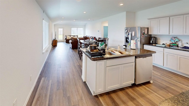 24327 Copperleaf Bay Ln, Spring, TX 77373 - kitchen featuring stainless steel appliances, light wood-type flooring, dark countertops, an island with sink, and recessed lighting