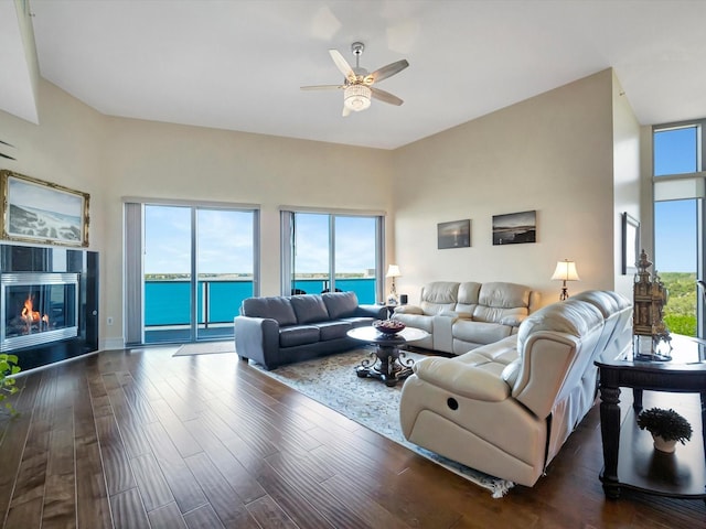 living room with dark wood-style floors, ceiling fan, a glass covered fireplace, and a healthy amount of sunlight
