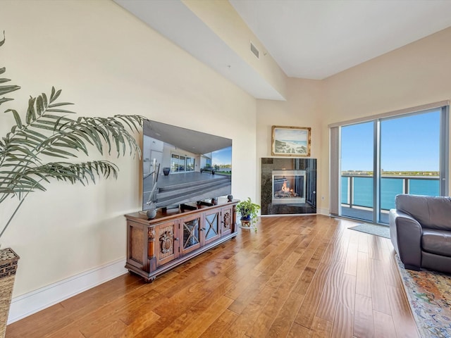 living area with baseboards, visible vents, wood finished floors, and a premium fireplace