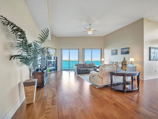 living room featuring baseboards, wood finished floors, and ceiling fan