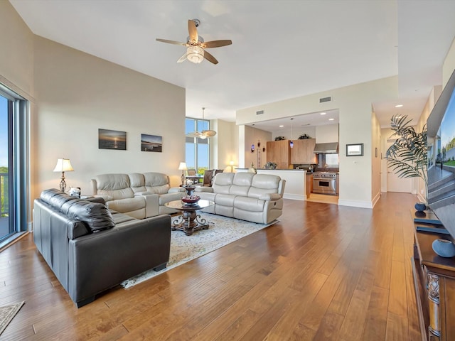 living area featuring baseboards, visible vents, a ceiling fan, and hardwood / wood-style floors