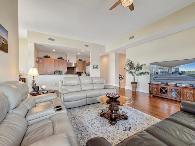 living room with baseboards, ceiling fan, visible vents, and wood finished floors