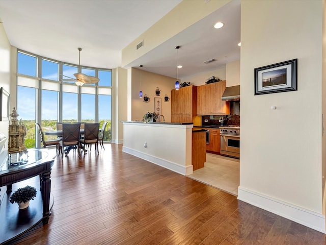 kitchen with floor to ceiling windows, brown cabinets, high end range, dark countertops, and decorative backsplash