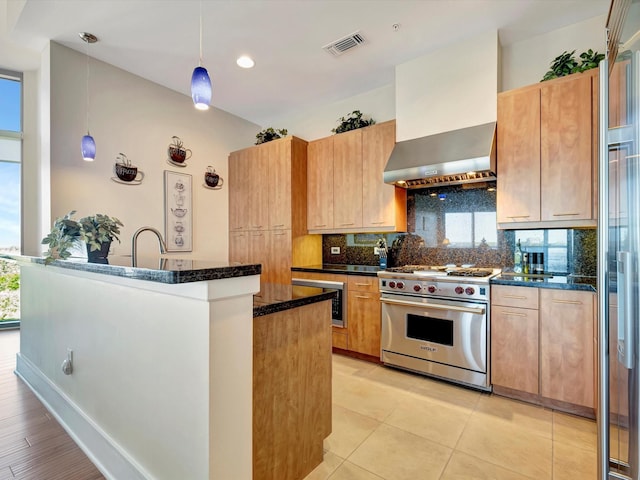 kitchen featuring wall chimney exhaust hood, tasteful backsplash, appliances with stainless steel finishes, visible vents, and dark stone counters