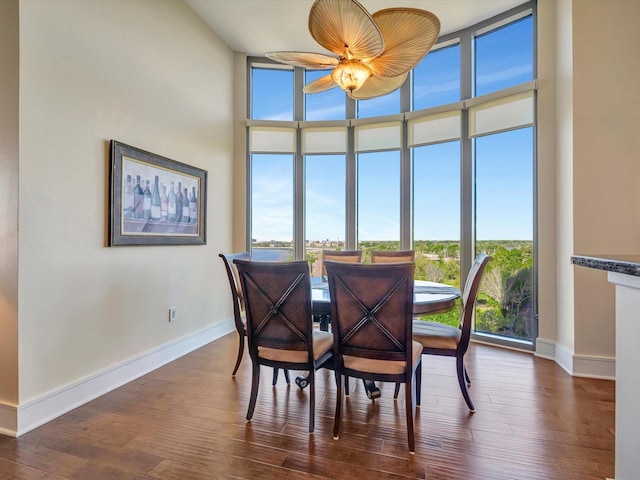 dining space featuring dark wood-type flooring, a wealth of natural light, a ceiling fan, and a wall of windows