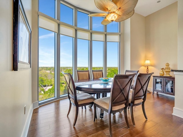 dining space featuring baseboards, a high ceiling, wood finished floors, and a wall of windows
