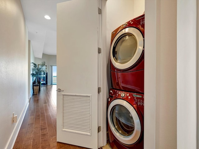 laundry room with stacked washer and clothes dryer, baseboards, wood finished floors, laundry area, and recessed lighting