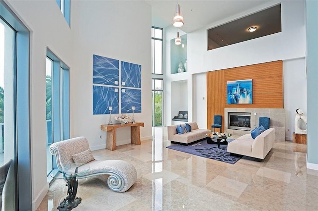 living area featuring a high ceiling, baseboards, and a fireplace