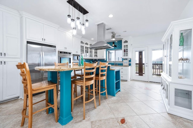 kitchen with white cabinets, plenty of natural light, island exhaust hood, and built in appliances