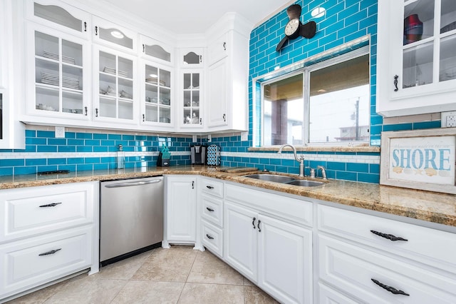 kitchen featuring a sink, stainless steel dishwasher, glass insert cabinets, light tile patterned floors, and decorative backsplash